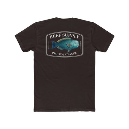 A close-up view of the back of a brown premium cotton t-shirt. The centerpiece is a detailed, vibrant illustration of a blue Parrotfish, reflecting its natural colors. The Reef Supply brand logo is arched over the top of the fish, with 'Pacific & Atlantic' text printed in a clean font beneath it, highlighting our coastal inspiration