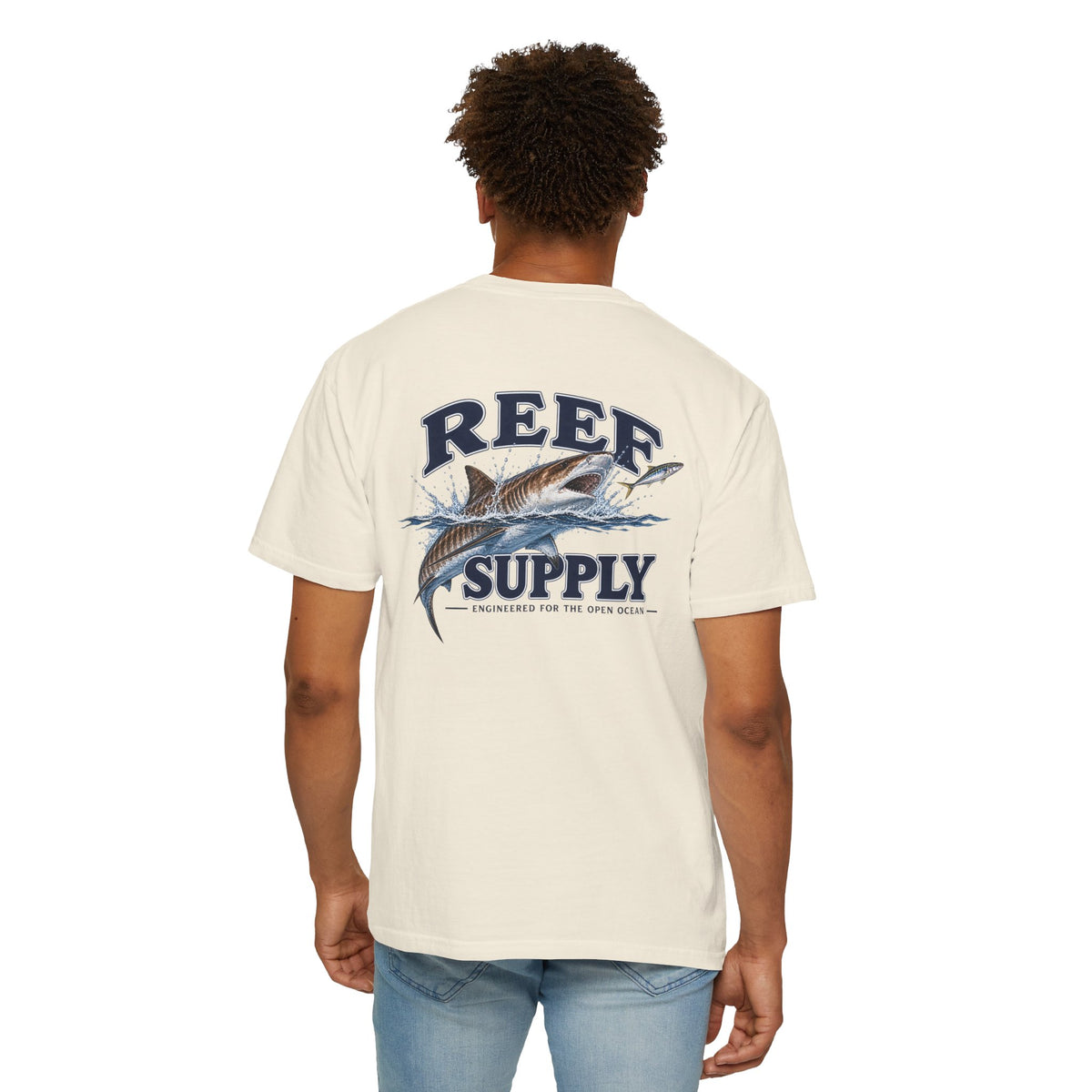 Back view of a person wearing a cream Reef Supply Tiger Tee with a fish graphic.