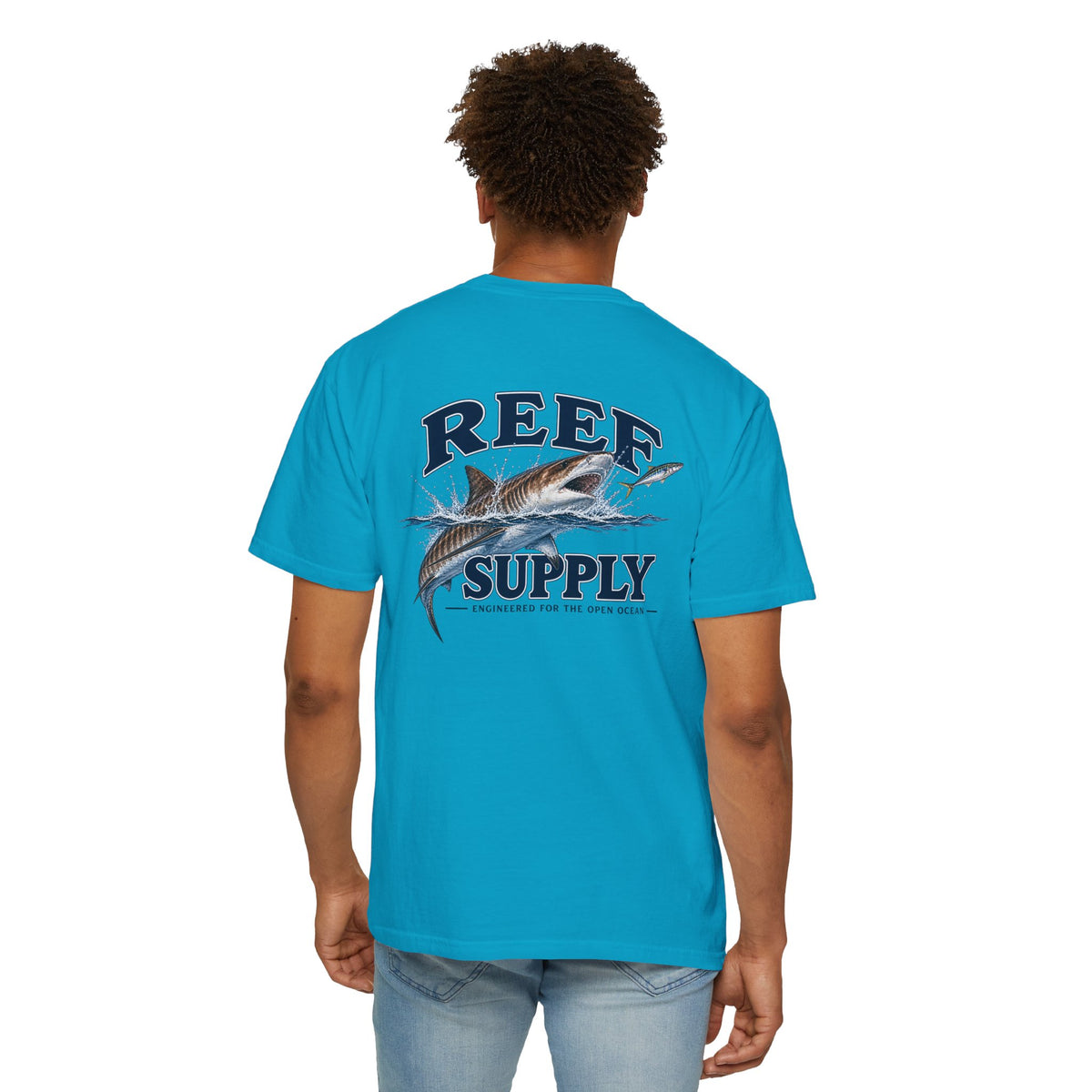 Back view of a man wearing a turquoise Reef Supply Tiger Tee featuring a shark graphic.