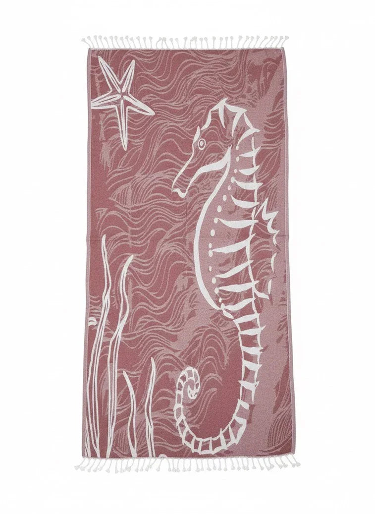 Beach towel with seahorse and starfish design on a pink background