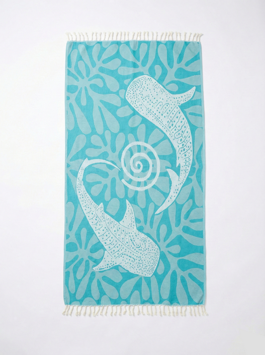 Turquoise towel with white whale and shell design on a white background